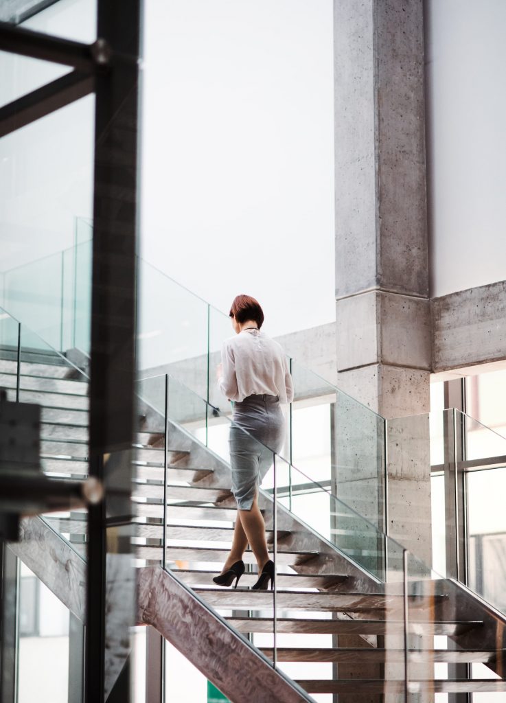A Rear View of Young Businesswoman Walking up the Stairs in Office Building